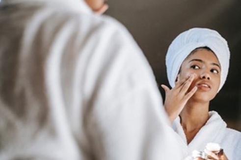 Young woman applying moisturizer after anti-aging treatments